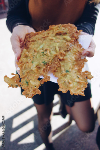 Woman holding Tortillita de camarón (shrimp tortillita) in hands. Typical tapa of Cadiz, Andalusia, Spain photo