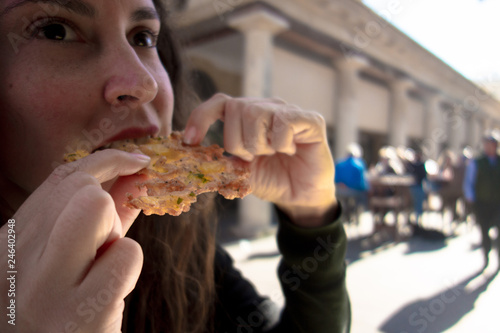 Woman eating tortillita de camarón (shrimp tortillita). Typical tapa of Cadiz, Andalusia, Spain