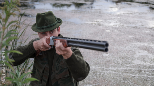 Hunter with green hat shooting with rifle