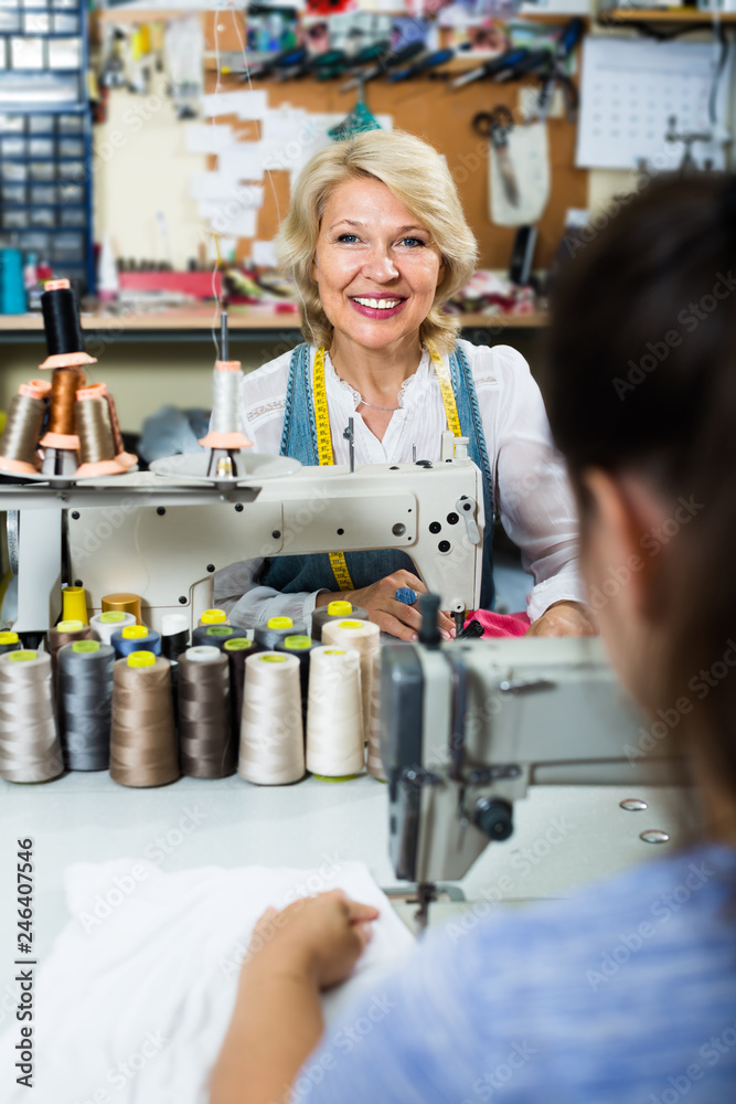 professional mature woman tailor using sewing machine