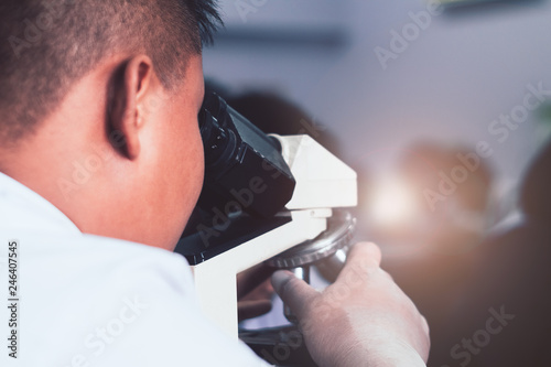 Students wear rubber gloves and looking microscope in science class