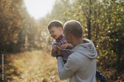 Young father holding his little son circling on hands. Autumn nature.