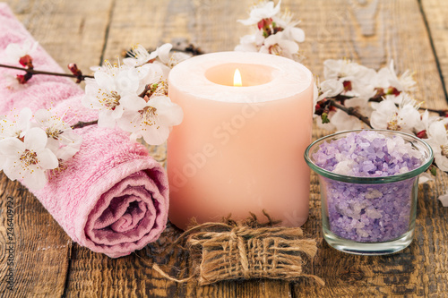 Soap  sea salt in glass bowl with towel for bathroom procedures and burning candle with flowering branch of apricot tree