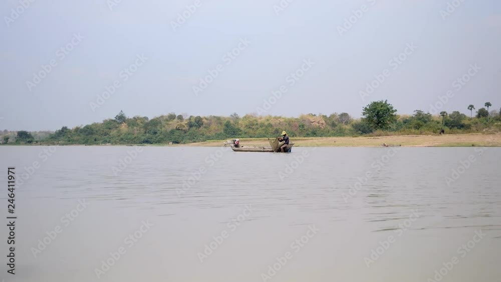 fisher in dugout canoe pulling drop net out of the river, catching shrimps, baiting net and pushing it deeper into a river fisher in dugout canoe pulling drop net out of the river, catching shrimps, baiting net and pushing it deeper into a river