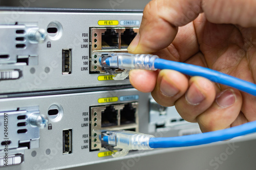 Hand of man holding The network cables to connect SFP module port in the Datacenter room, concept Communication technology