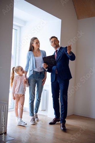 handsome broker showing room while standing near attractive woman and kid