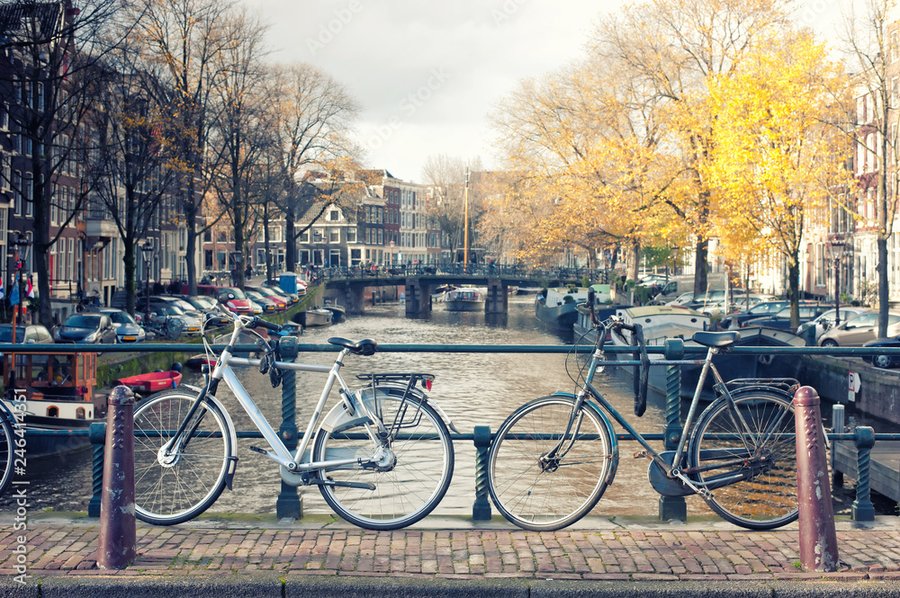 Bicycles lining a bridge over the canals of Amsterdam, Netherlands in vintage style.