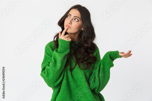 Beautiful thinking young woman dressed in green sweater posing isolated over white wall background.