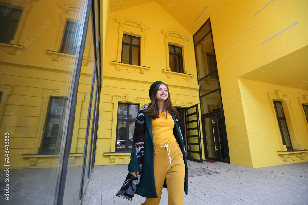 beautiful young brunette woman in a yellow dress and cap near the yellow building beautiful young brunette woman in a yellow dress and cap near the yellow building