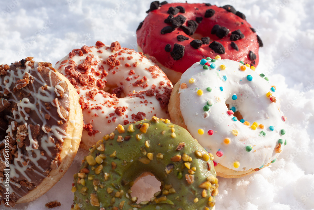 tasty colorful donuts in the snow