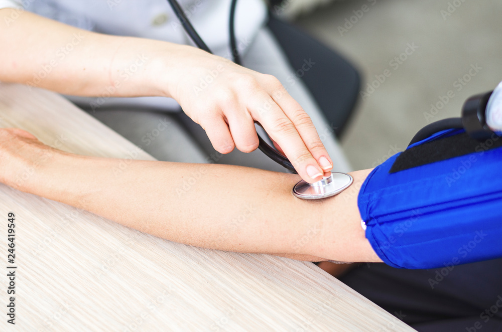 Closeup of measuring patient's blood pressure with sphygmomanometer.