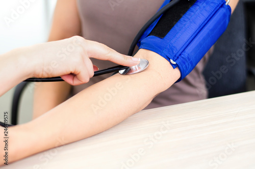Closeup of stethoscope bell pressing brachial artery during blood pressure measurement photo