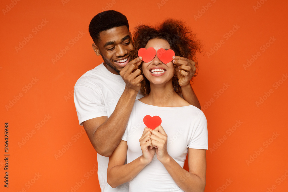 Obraz premium Young couple holding red love hearts over eyes