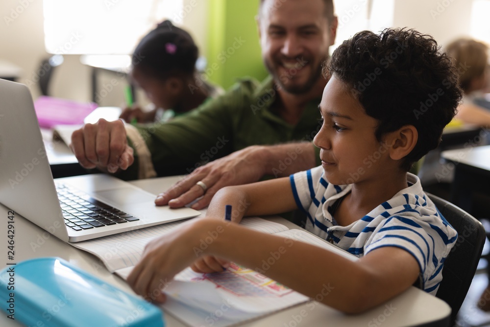 Young school teacher helping boy with study on laptop in Young school teacher helping boy with study on laptop in