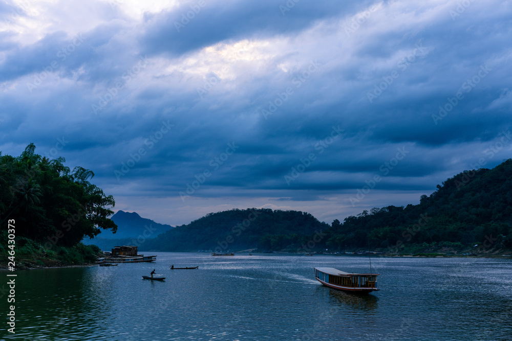 Sunset at mekong river. Blue hour with a lot of clouds. Some boats in the river. Cloudy scene in luang prabang, laos