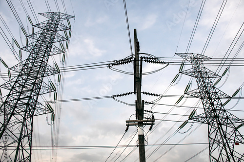 Electricity pole against blue sky clouds in dawn time, Transmission line of electricity to rural, High voltage electricity pole on bright sky clouds background, electricity transmission pylon photo