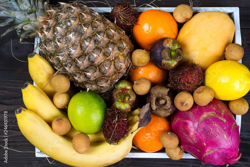 Fototapeta Naklejka Na Ścianę i Meble -  Fresh exotic fruits in a wooden box, top view with many colorful ripe fruits