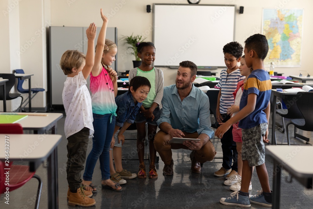 School kids raising hands while teacher teaching