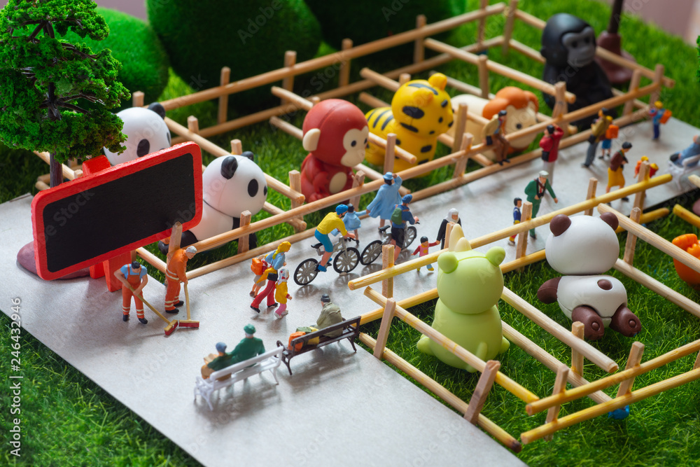 A self constructed miniature toys concept of people at the zoo - school kids, old people sitting on benches, cleaners cleaning the zoo.