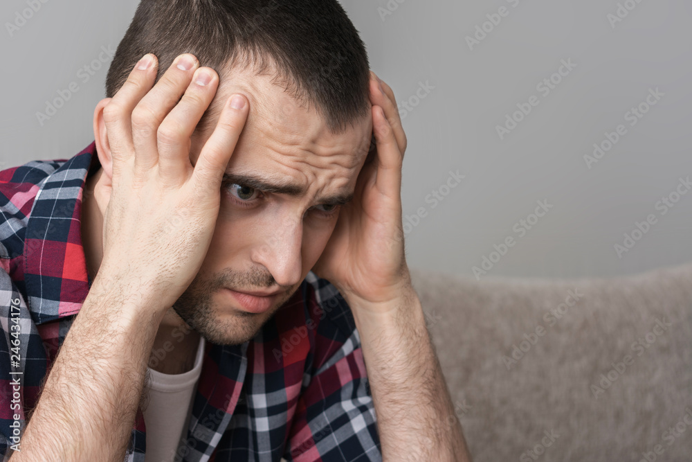 A male has a headache, squeezes his head with his hands, close up A male has a headache, squeezes his head with his hands, close up