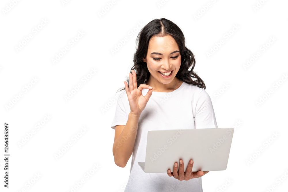 young asian woman using laptop and showing ok gesture isolated on white young asian woman using laptop and showing ok gesture isolated on white