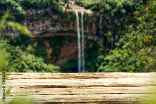 Wooden table on the background of a waterfall on a summer day 
