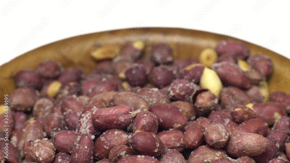 Raw unpeeled peanuts fried with salt. Rotation. Snack closeup. Peanuts in a bowl. Selective focus. Isolated on white. Studio shot. Healthy food concept. Raw unpeeled peanuts fried with salt. Rotation. Snack closeup. Peanuts in a bowl. Selective focus. Isolated on white. Studio shot. Healthy food concept.
