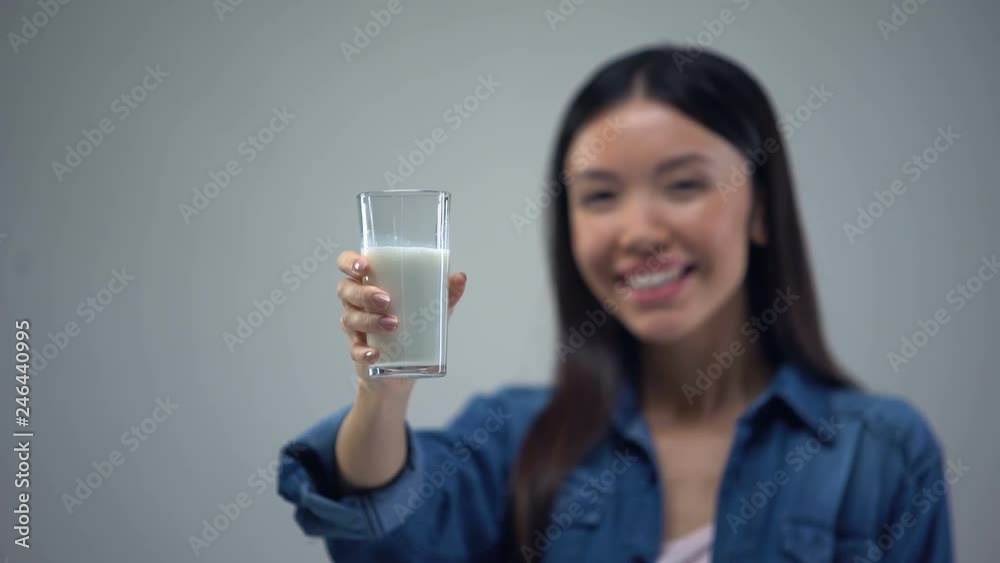 Cheerful woman showing glass of milk into camera, useful bacteria for health Cheerful woman showing glass of milk into camera, useful bacteria for health