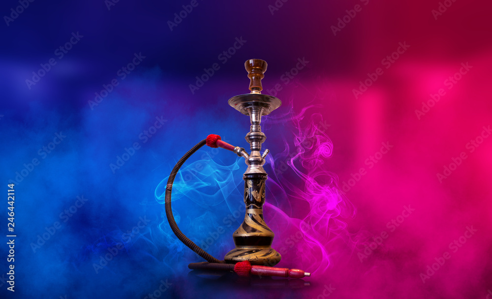Smoking hookah on the background of an empty room. Multicolored neon light. Searchlight, laser blue and pink rays, smoke. Smoking hookah on the background of an empty room. Multicolored neon light. Searchlight, laser blue and pink rays, smoke.