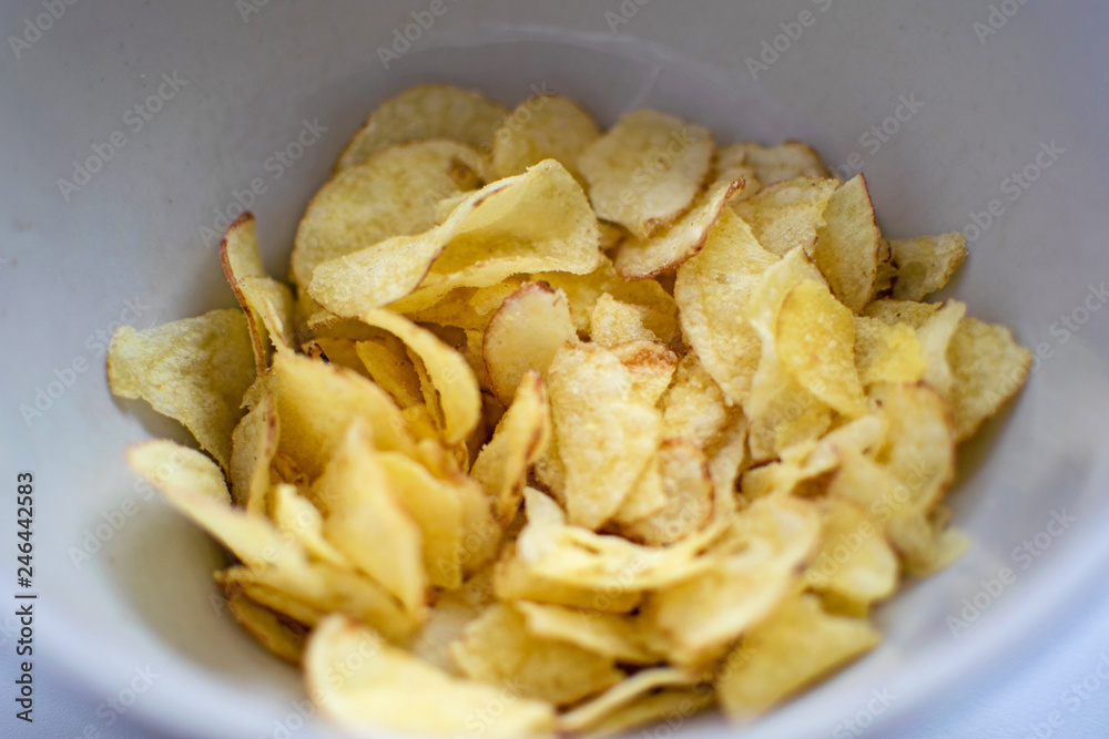 Potato chips in a plate on a white background. A white plate with tasty potato chips.