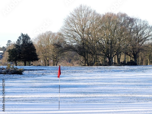 Snow covered golf course with red flag, Chorleywood Common, Hertfordshire, UK