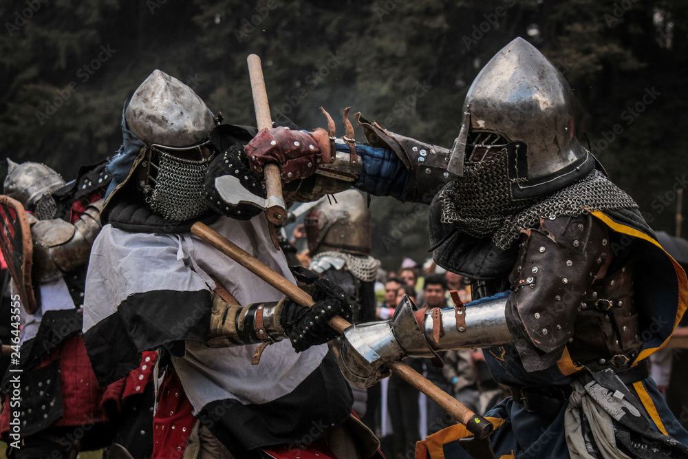 Medieval knights fighting with armor, beating with swords, axes and shields in festival