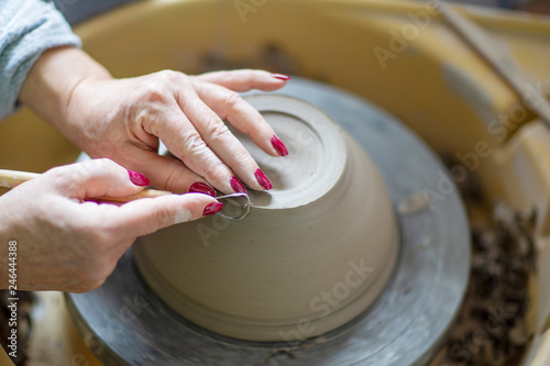 Womans hands making pot from clay on pottery wheel