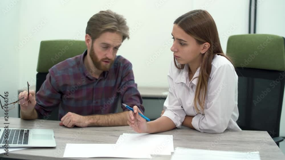 Bearded boss holding glasses in his hand points to a laptop screen while focusing on his staff on aspects of the new strategy or shortcomings of the work done. Bearded boss holding glasses in his hand points to a laptop screen while focusing on his staff on aspects of the new strategy or shortcomings of the work done.