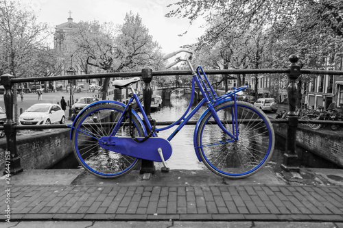 zdjecie-samotnego-niebieskiego-roweru-na-moscie-nad-kanalem-w-amsterdamie-tlo-jest-czarno-biale