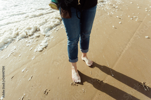 Woman walking barfoot at the beach and having foam at her toes