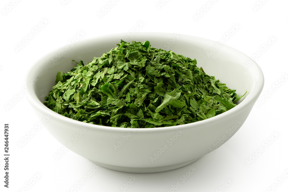 Dried chopped parsley in white ceramic bowl isolated on white. Dried chopped parsley in white ceramic bowl isolated on white.