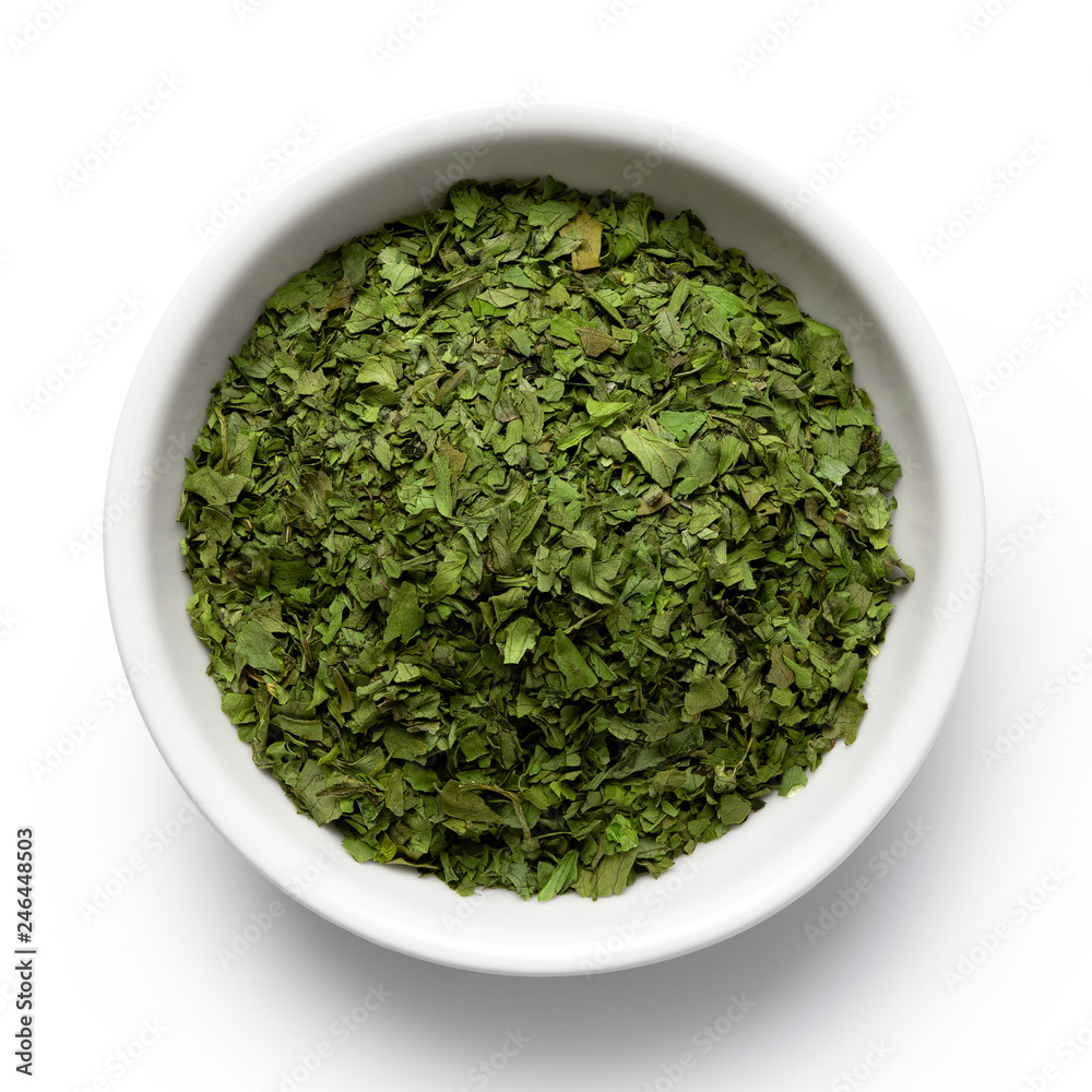 Dried chopped coriander leaves in white ceramic bowl isolated on white from above. Dried chopped coriander leaves in white ceramic bowl isolated on white from above.