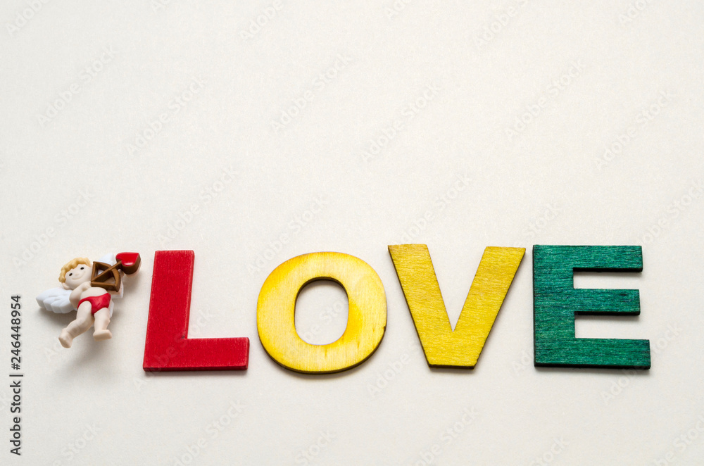 Obraz premium Love word made with colorful wooden letters and decorated with a little cupid against white background