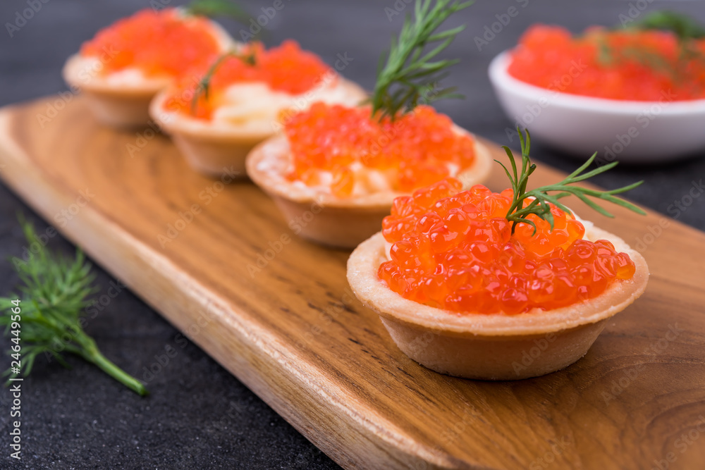 Canapes with salmon red caviar on a black  background