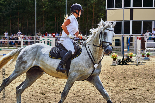 Young woman jockey in white dress and black boots, takes part in equestrian competitions. Close-up.