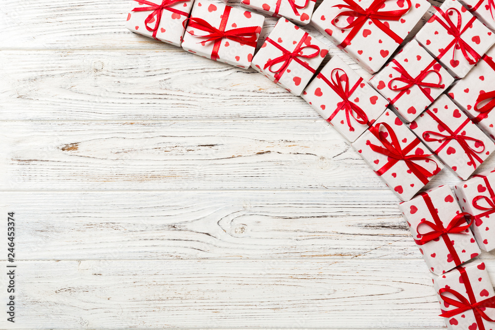 Fototapeta premium valentine or other holidays concept. Lots of Gift boxes on wood background top view. Presents in craft paper decorated with red ribbon bows and heart. top view with copy space for text frame