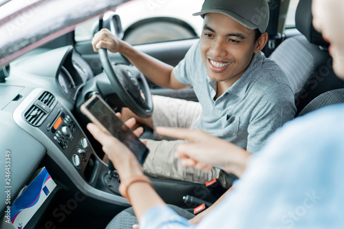 man driver looks passenger smartphone's to approved a new destination