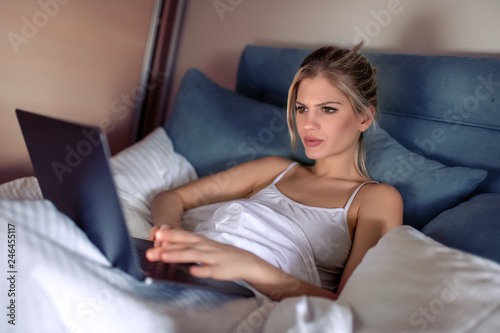 Pretty woman using her laptop in bed