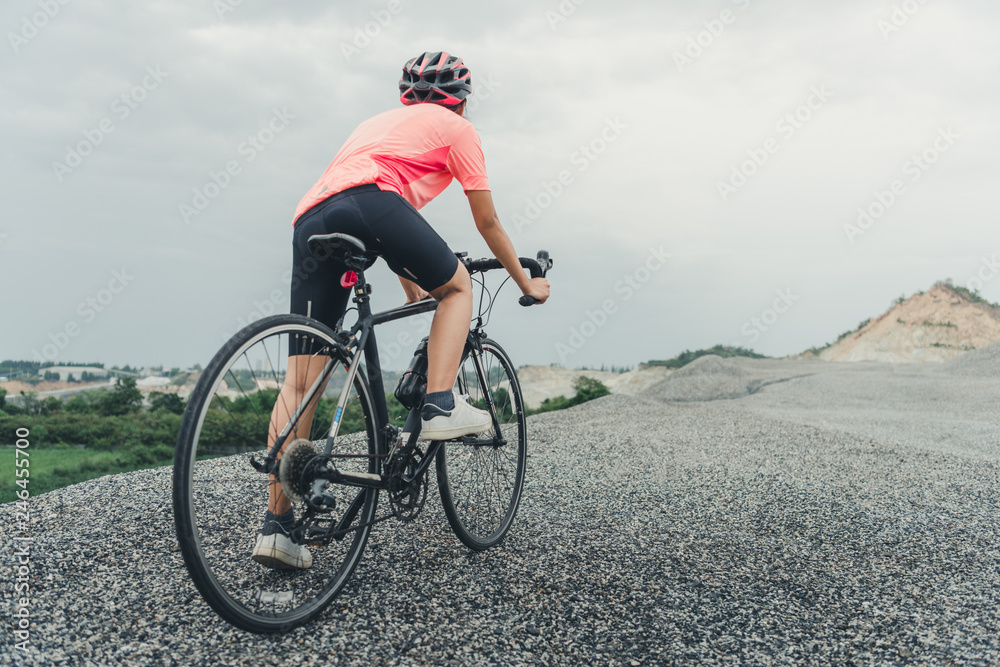 Young woman cyclist riding mountain bike on forest trail