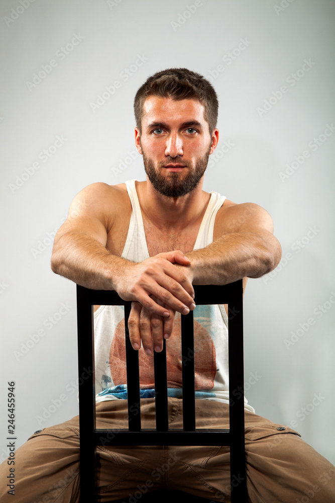 Obraz premium Portrait eines jungen bärtigen Mannes, der im Studio auf einem Stuhl sitzt und nachdenkt