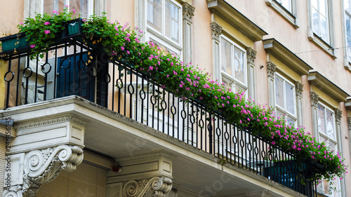 Decotated balcony with flower pots. Pots of pink petunias. Floral design of balcony. Decorated exterior