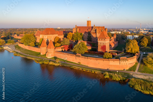 Medieval Malbork (Marienburg) Castle in Poland, main fortress of the Teutonic Knights at the Nogat river. Aerial view in fall in sunset light. photo