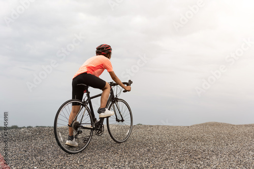 Road bike cyclist man cycling. Biking Sports fitness athlete riding bike on an open road to the sunset. Cyclist biking on road bike with sun flare.