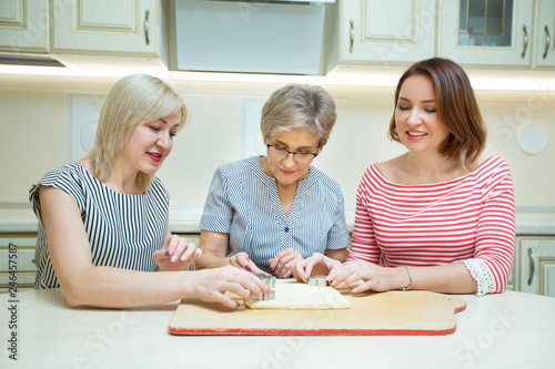 three stylish adult women making cookies in the kitchen